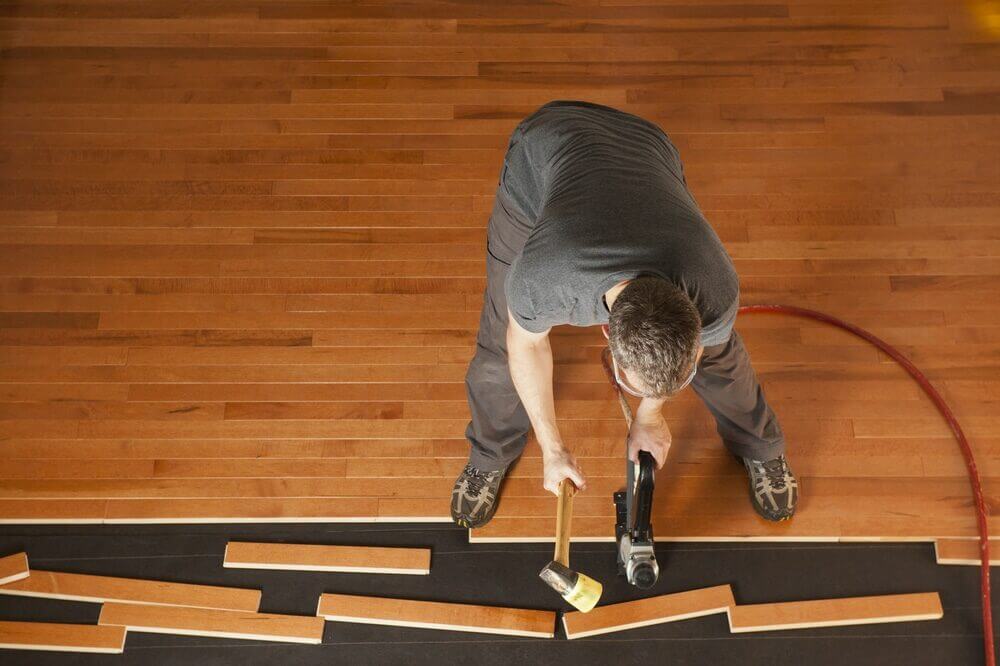 Professional installing engineered hardwood flooring in a modern home