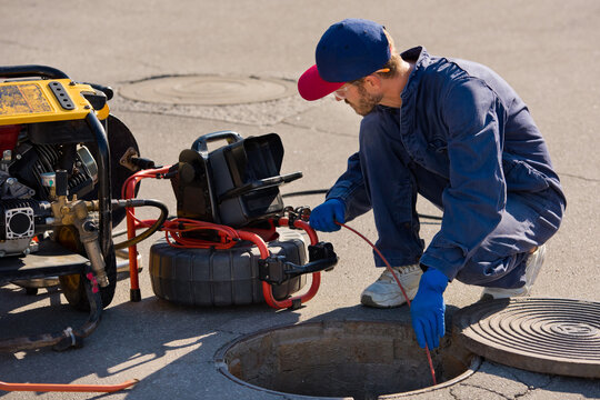 Technician performing sewer repair process using trenchless pipe lining and inspection camera